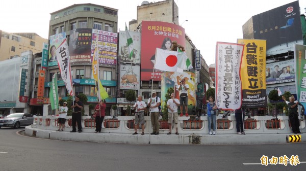 公投護台灣聯盟嘉義旗隊在嘉市地標中央噴水圓環舉旗歡迎田邊憲司,田邊也拿著日本國旗加入舉旗行列,吸引路過民眾目光。
(記者丁偉杰攝)