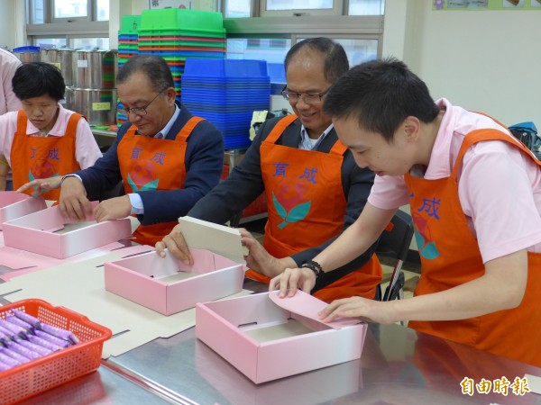 前行政院長游錫堃、立法委員高志鵬在憨兒的指導下，學習摺禮盒需要的紙盒。（記者李雅雯攝）