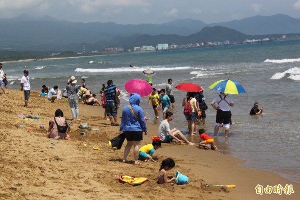 遊客紛紛到海邊戲水消暑。(記者林欣漢攝)