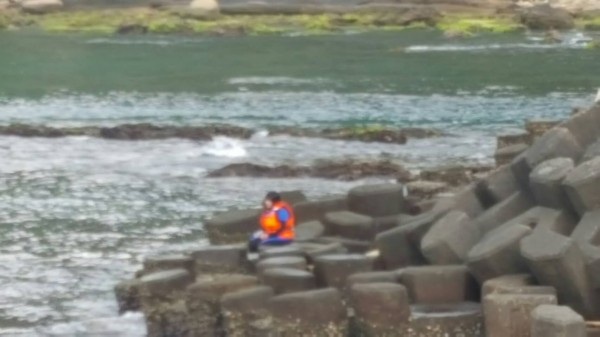 陳女坐在海邊路過的民眾打趣的說誤以為是美人魚，後來擔心是女子想不開，立刻通報１１９救人（記者吳昇儒翻攝）