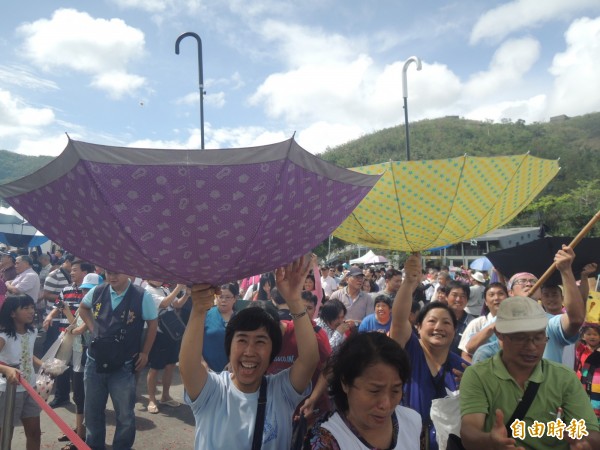 遊客把雨傘倒放接包子。（記者江志雄攝）