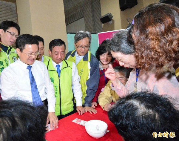 彰化縣長魏明谷(左)親自坐莊擺碗公與老人家們大玩「十八豆仔」,現場笑聲不斷。(記者湯世名攝)