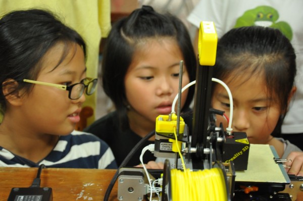 崇倫國中機器人社將3D列印課程帶至南投縣溪南國小,小學生們對3D列印非常好奇,專注地看著3D印表機上的作品。(黃忠志提供)