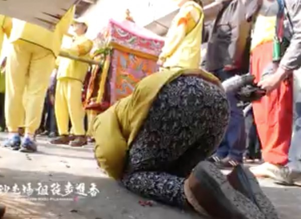 婦人跪地不斷向媽祖神轎磕頭。(翻攝黃朝業臉書)