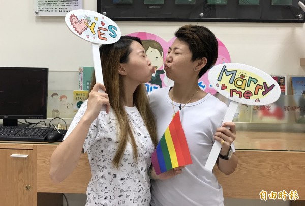 陳湘霖（右）、林慧瑄（左）在新營戶政所完成同性伴侶註記後，俏皮的嘟嘴玩親親拍照。（記者楊金城攝）