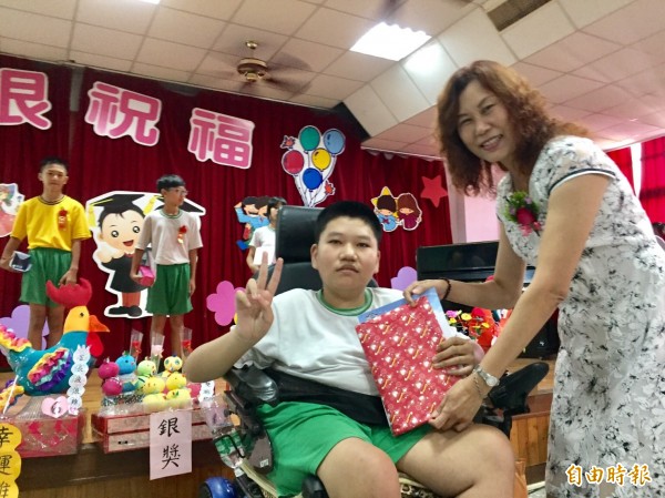 虎尾安慶國小應屆畢業生李郁竣先天肢體障礙肌肉萎縮仍天天上學,獲校長李瑪莉(右)頒勤奮學習獎。(記者廖淑玲攝)