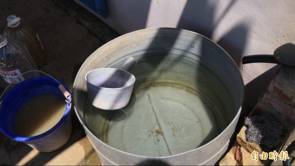 王老先生將泥水沈澱後，將上層乾淨水放置到右邊的鐵桶。（記者蔡宗憲攝）
