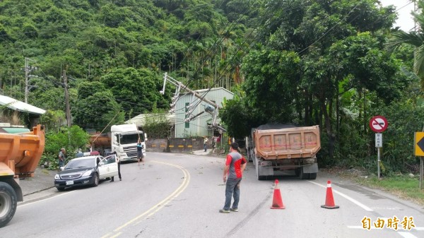 一輛砂石車閃車不慎撞倒電線桿，造成電桿嚴重傾斜，阻礙往來交通。（記者劉濱銓攝）