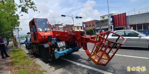 吊車漏油2公里，機車連環滑倒，駕駛舉牌提醒用路人小心。（記者簡惠茹攝）