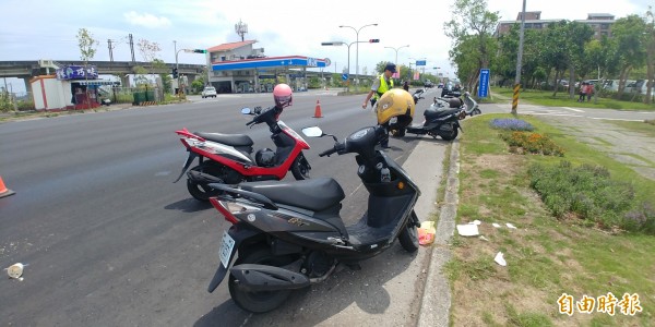 吊車漏油2公里，機車連環滑倒，駕駛舉牌提醒用路人小心。（記者簡惠茹攝）