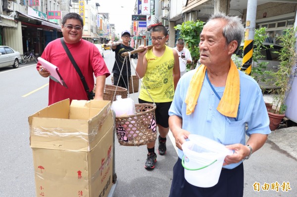 頭城鎮城西里長李長鎮（右）及頭城鎮民代表游錫財（白衣者）仿效早年民間組織募孤飯的習俗，在中元節前夕於大街小巷向店家、居民募飯。（記者林敬倫攝）