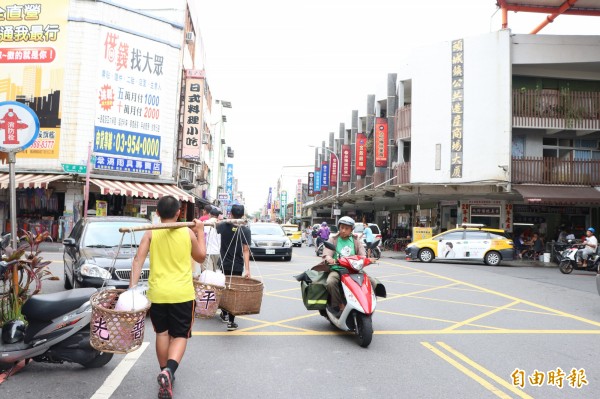 民間組織挑著擔子向民眾收孤飯的景象，近年在頭城街頭重現。（記者林敬倫攝）