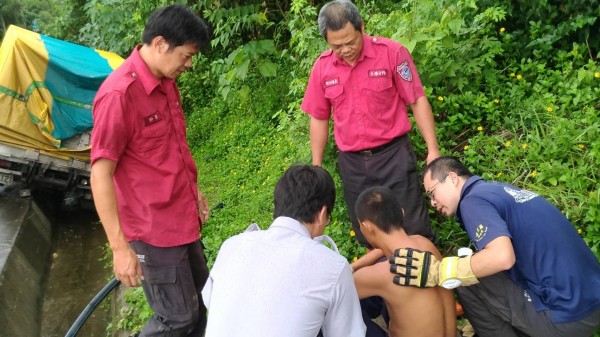 男駕駛（打赤膊者）脫困後驚魂未定，消防人員上前安撫。（記者曾迺強翻攝）