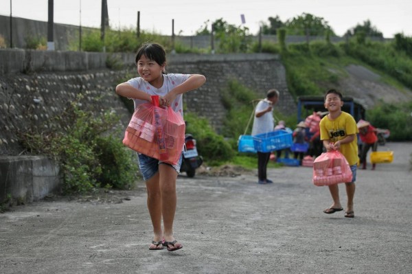 小孩提著金銀紙，走上濁水溪堤防，跟著長輩拜溪王。（圖：許震唐提供）