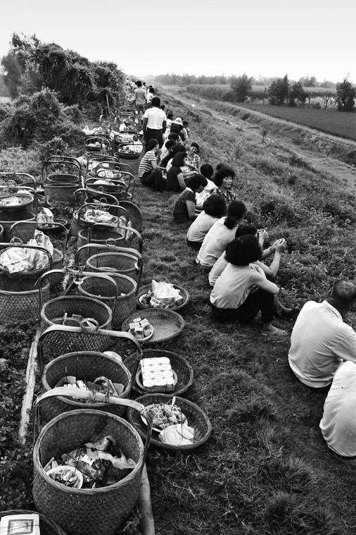 28年前，濁水溪河堤未整治水泥護堤，家家戶戶挑著扁擔，坐在土堤等待準備祭拜溪王。（圖：許震唐提供）