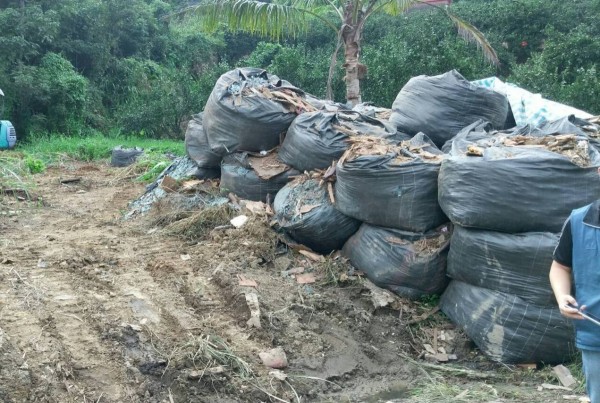 新竹縣峨眉分駐所員警在大貨車翻覆的地點約100公尺外農地,查獲非法堆置的廢棄物太空包。(警方提供)