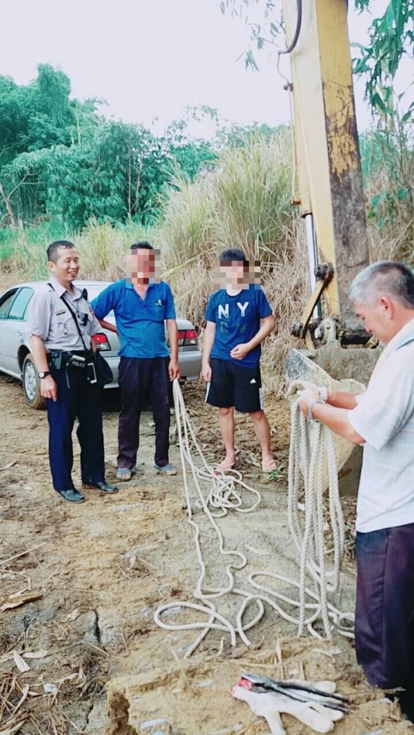 民雄警分局北斗所派出所副所長吳明誠（左1）請挖土機駕駛（右1）協助，幫助誤入鳳梨田的轎車脫困。（記者曾迺強翻攝）