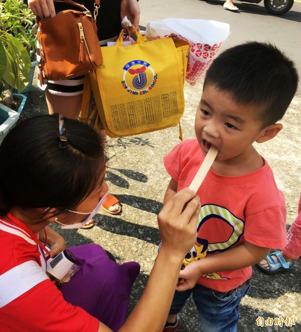 幼兒園老師為學童檢查口腔黏膜、舌頭、牙齦和嘴唇，是否出現水泡潰瘍等腸病毒症狀。（記者張忠義攝）