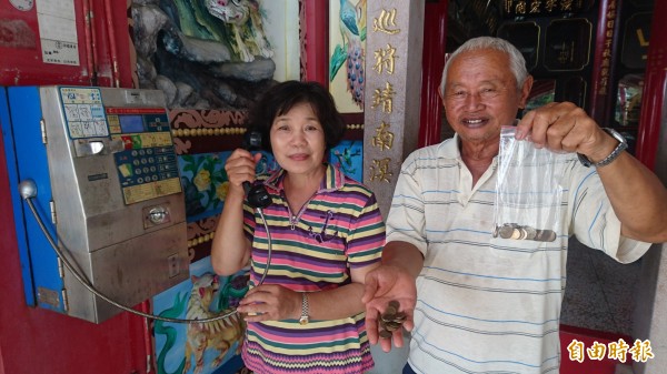 廟公王州成(右)和太太王吳寶貴(左)把庄內僅存的公用電話當成寶貝,自備破幣三不五時就打一打電話,整整打了11年,以免得公用電話因為沒人使用,被中華電信拆機收回。(記者楊金城攝)