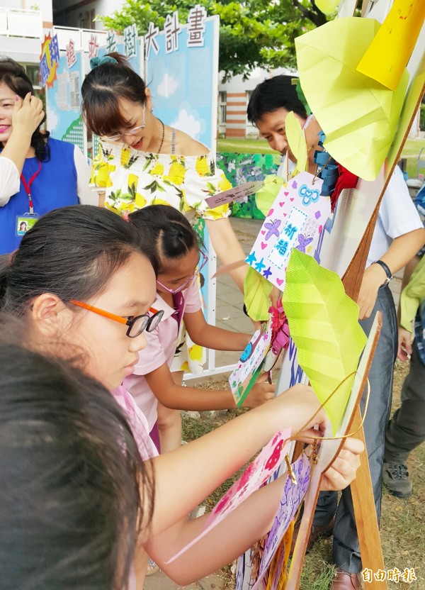 師生懸掛祈福卡，祝福雨豆樹奶奶早日康復。（記者陳文嬋攝）