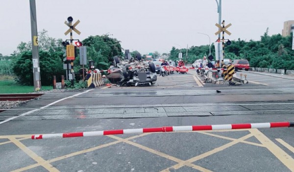 休旅車翻車，車頭越過平交道柵欄，幸好不影響火車通行。（記者楊金城翻攝）