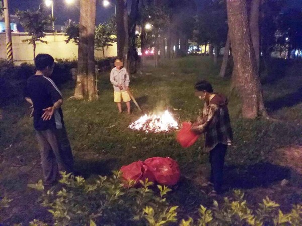 三男於公園草地上燒金紙。（記者陳文嬋翻攝）