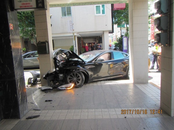 特斯拉Model S款的高階四門轎車，疑閃避轉彎車輛，失控衝撞騎樓柱子，整個車頭凹陷、毀損。（記者方志賢翻攝）