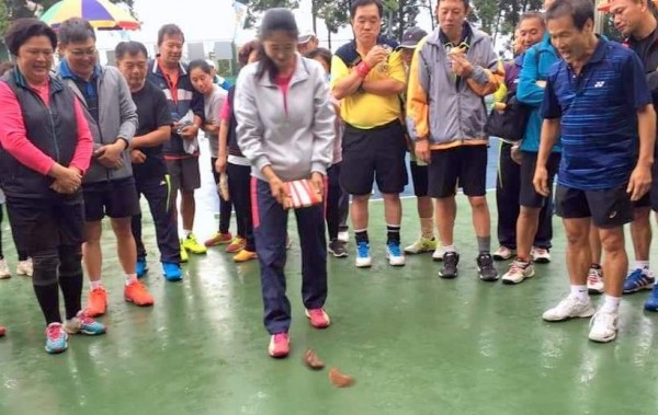 南投縣魚池鄉三藏杯軟式網球錦標賽，12日社會男女團體組賽程，因雨受阻，最後以「擲筊」聖杯數多寡決定輸贏，吸引大家圍觀。（記者謝介裕翻攝）（記者謝介裕攝）