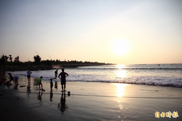 嘉義縣布袋鎮的小確幸海灘，海上夕陽景色相當美麗，也有民眾前往戲水。（記者林宜樟攝）