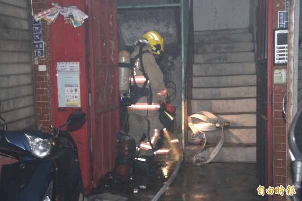 地下室竄出濃煙，消防隊員佈水線進入救災（記者吳昇儒攝）