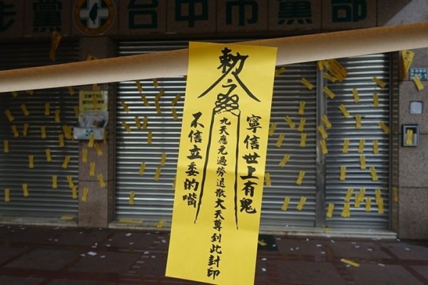 民進黨台中市黨部前遭張貼上百張符咒，表達對多項議題不滿。（記者李忠憲翻攝）