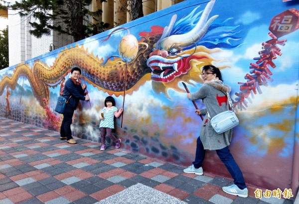 居住桃園市中壢區的林先生一家三口,也趁週末返回苗栗老家,今天到(火旁)龍3D立體彩繪扮起舞龍手,拍照留念。(記者彭健禮攝)
