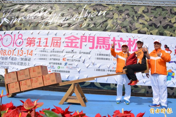自桃園的周姓選手(右二)獲得「 翹翹板」那端約與體重等重的金門高粱酒,獲得金門縣副縣長吳成典(右三)的祝福。(記者吳正庭攝)