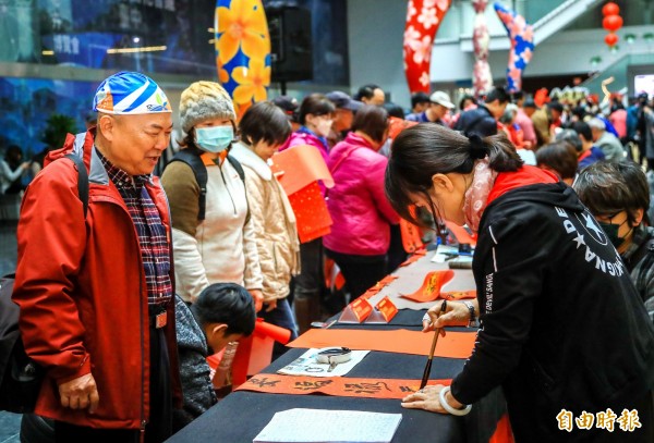 書法家揮毫寫春聯，索取的民眾大排長龍。（記者張菁雅攝）