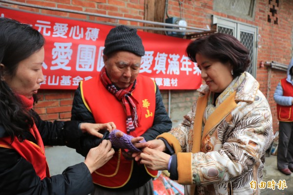 冠軍磁磚副董事長王桂鳳（右）與華山基金會苗栗縣站長杜靜容（左）為楊爺爺戴手手套保暖。（記者鄭名翔攝）