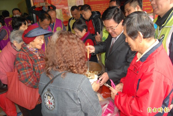 彰化市長邱建富（右二）在大東門福德祠舀麻油雞酒給信眾食用。（記者湯世名攝）