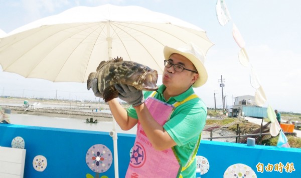 遊客永安區抱石斑魚，開心合照留念。（記者陳文嬋攝）