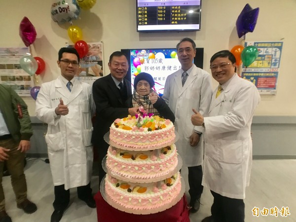 新北市立聯合醫院醫療團隊今天早上為105歲的郭周鳳(中)歡慶康復成功出院,準備大蛋糕賀「重生」,左起為骨科醫師李忠謙、新北市衛生局長林奇宏、聯合醫院院長項正川、麻醉科醫師鄒樂起。(記者陳心瑜攝)