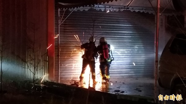 消防人員鋸鐵門滅火。(記者江志雄攝)
