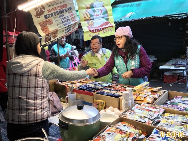 民進黨南投縣長參選人洪國浩的妻子侯淑玲（右）到水里鄉市場拜票，黨部主委陳昭煜（中）也向選民懇託。（記者劉濱銓攝）