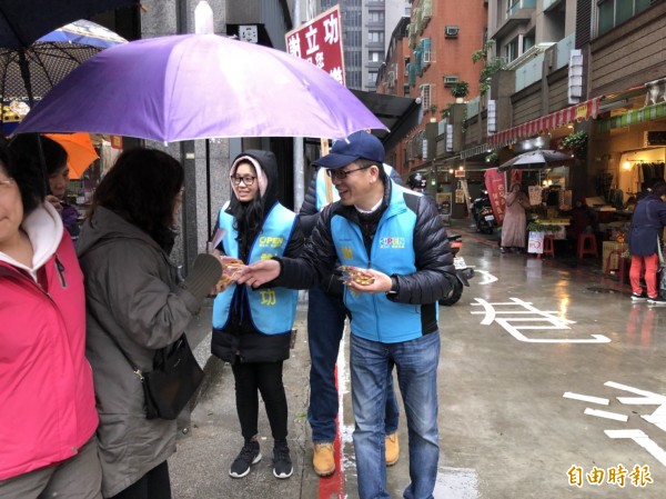 年節腳步逼近，國民黨基隆市長參選人謝立功到傳統市場發放金元寶、金幣巧克力，要大家吃在嘴裡、甜蜜過年。（記者俞肇福攝）