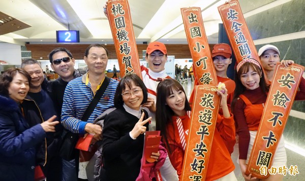 舞者拿標語與旅客互動,發紅包、合照,除了讓旅客感受到春節氣氛,也瞭解加速通關的小撇步。(記者朱沛雄攝)