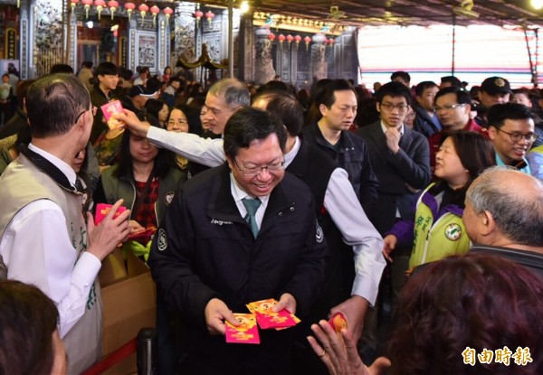 桃園市長鄭文燦勤走市轄宮廟發放春節福袋，民眾排隊爭拿市長福袋。（記者李容萍攝）