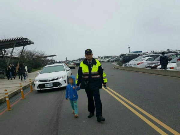 新北市金山警分局員警在野柳地質公園前的停車場，找到走失的三歲高姓男童，將其帶回機動派出所。（記者俞肇福翻攝）