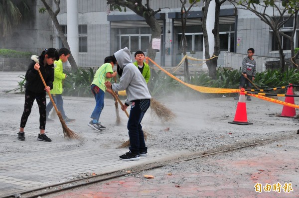 災後校園還多處地面有破碎的水泥磁磚塊，開學第一天，孩子們拿起掃帚打掃整理。（記者花孟璟攝）