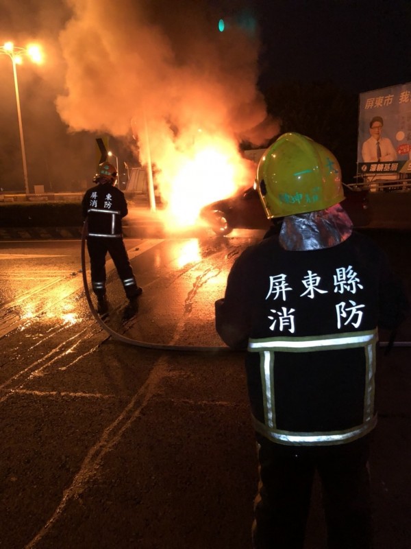 自小客車自撞中央分隔島後起火燃燒，消防人員到場滅火。（記者葉永騫翻攝）