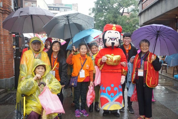 儘管下雨，長輩們撐傘、穿雨衣也要一起來參加走春活動。（弘道基金會提供）