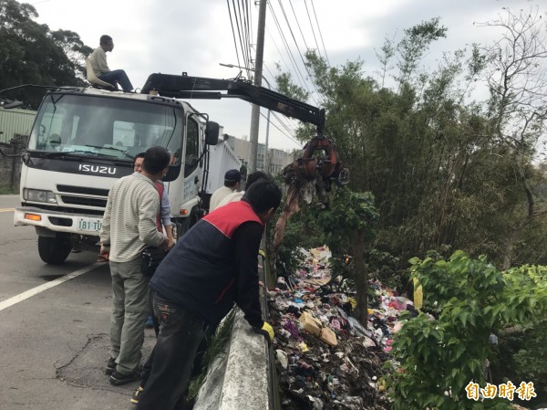 新竹市新香街的邊坡遭人丟置大批數千件二手衣物，新竹市環保局已前往蒐證及破袋，並查出可疑跡證，並請清潔隊協助清理。（記者洪美秀攝）