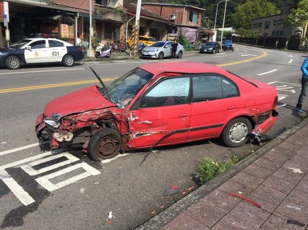 被撞的紅色轎車左側車頭全毀、駕駛座車門凹陷，所幸車內無人。（記者陳恩惠翻攝）