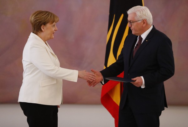 再度當選德國總理的梅克爾,自總統史坦邁爾(Frank-Walter Steinmeier)手中領取任命狀。(路透)